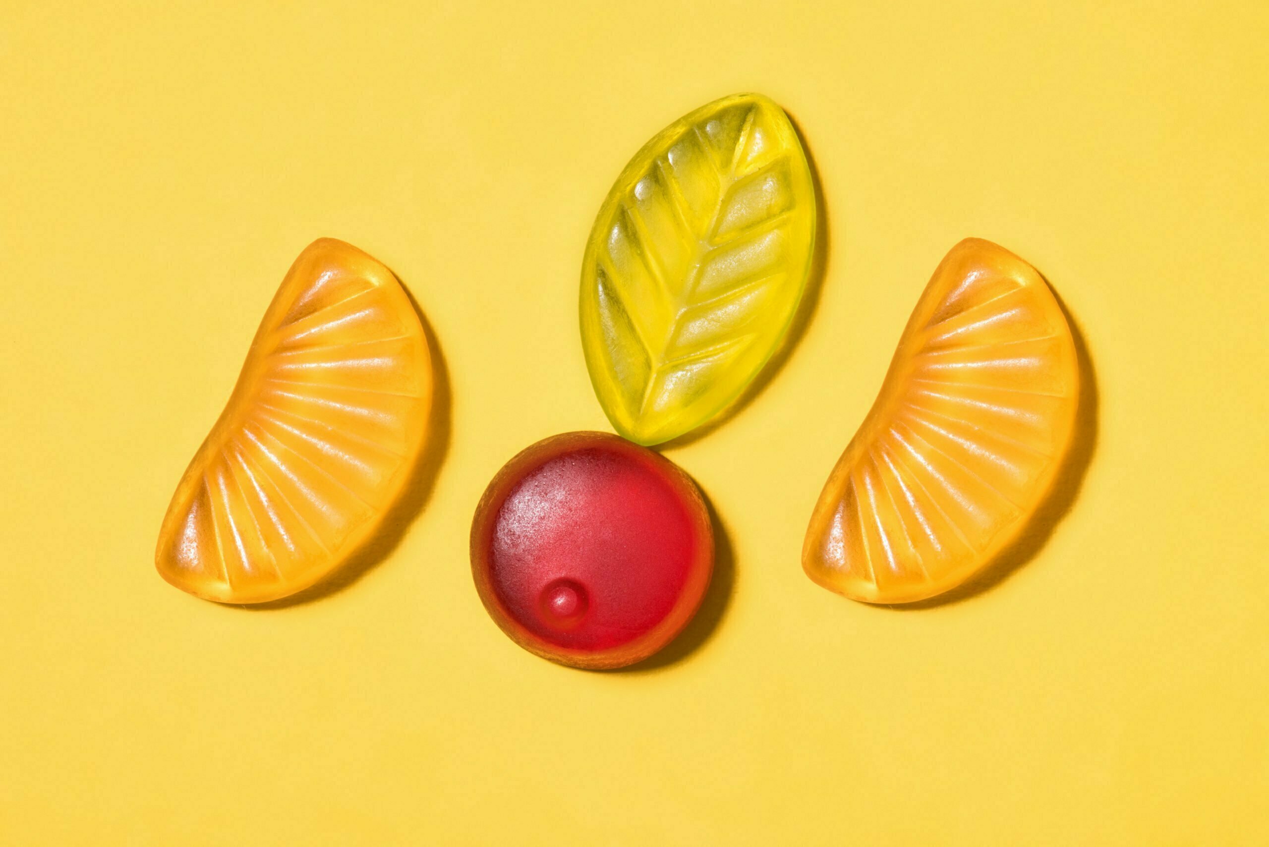 top view of tasty gummy fruits on yellow surface